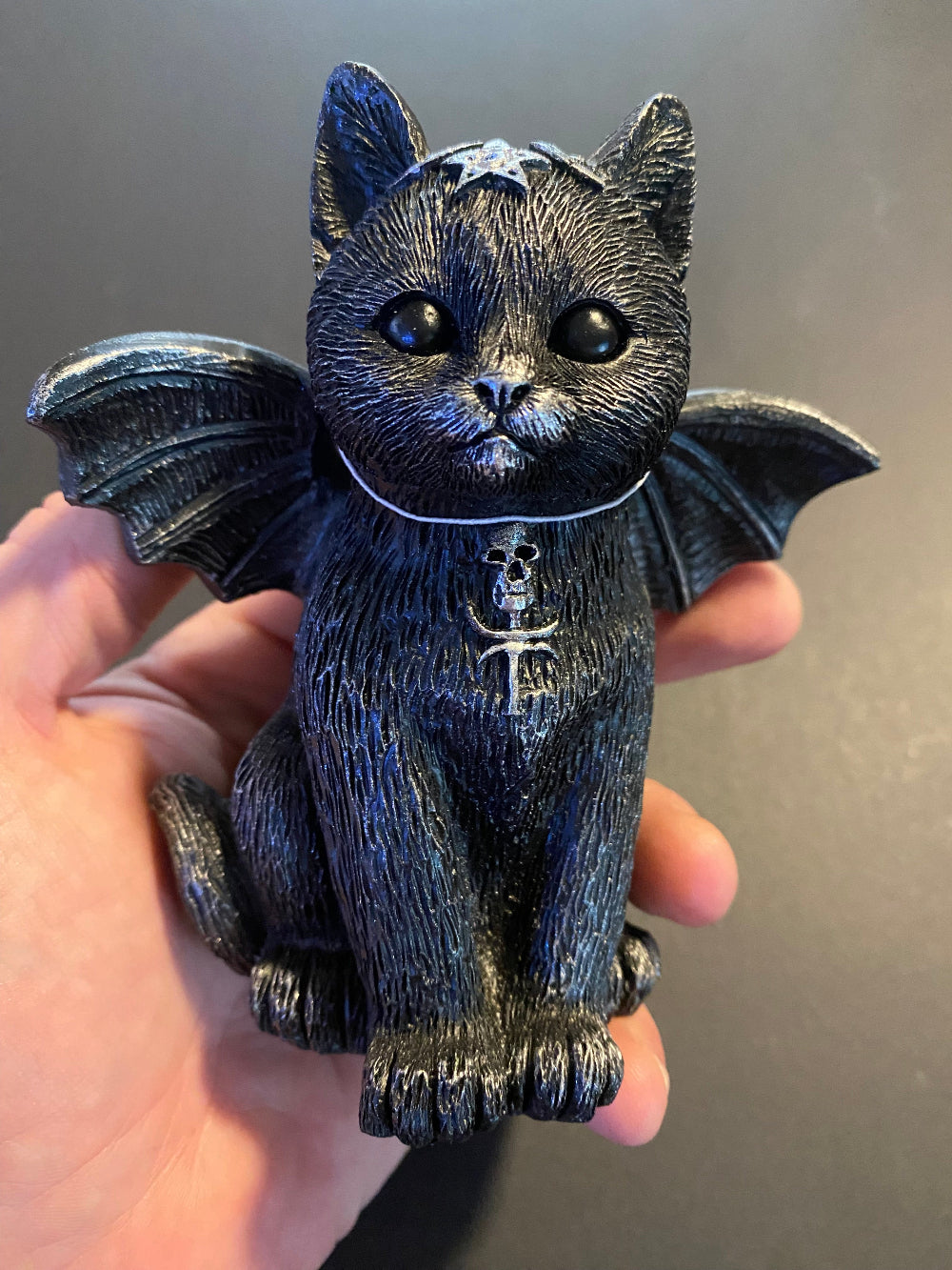 Gato wicca con alas en la mano